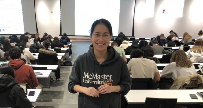 Lydia Chen stands in a large undergraduate lecture hall
